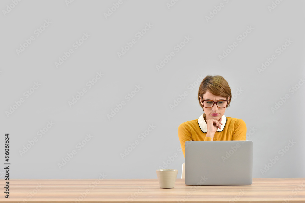 Office worker in front of laptop, grey background Office worker in front of laptop, grey background