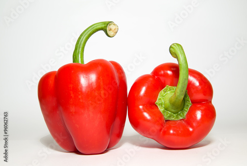 Two ripe red  peppers on over white