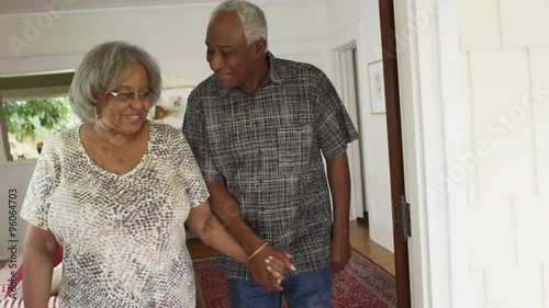Sweet black senior couple walking to couch smiling
