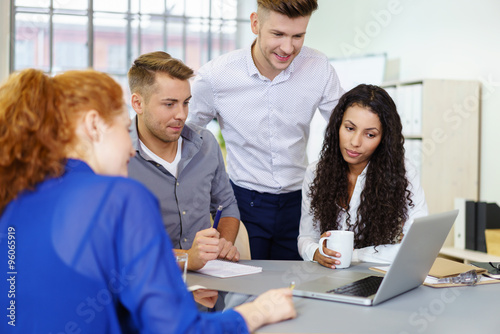 team im b  ro sitzt am schreibtisch und schaut auf notebook