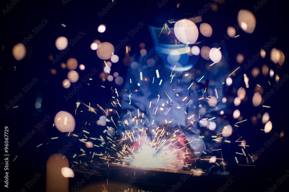 Employee welding steel with sparks using mig mag welder - focus on sparks. - obrazy, fototapety, plakaty 