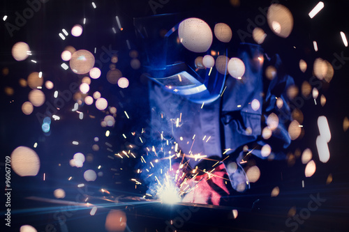Obraz na płótnie Employee welding steel with sparks using mig mag welder - focus on sparks