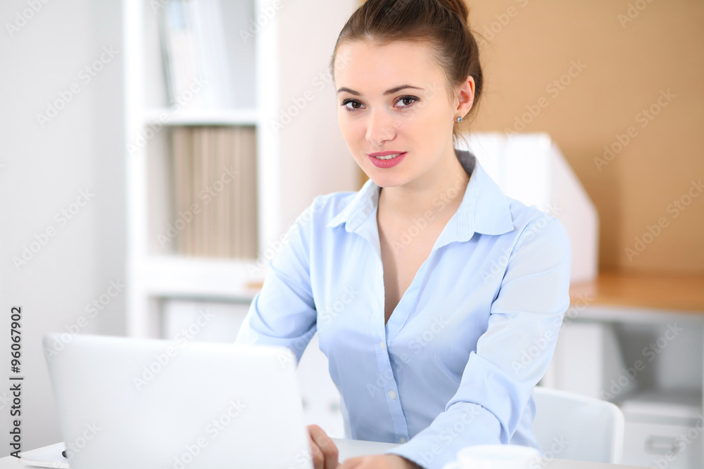 Young business woman working on laptop in office. Successful business concept. Young business woman working on laptop in office. Successful business concept.