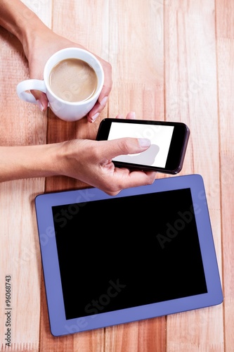 Businesswoman holding smartphone and coffee cup