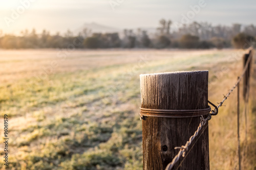 Sunrise on a frosty meadow and fence pole in South Africa