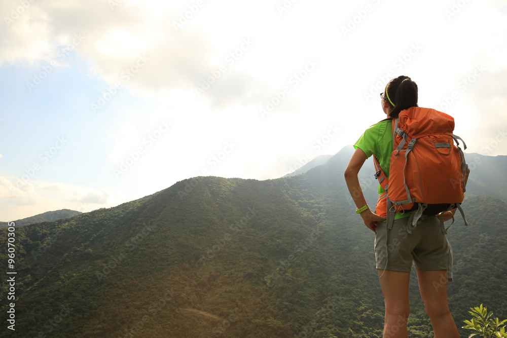 woman backpacker enjoy the view at mountain peak cliff