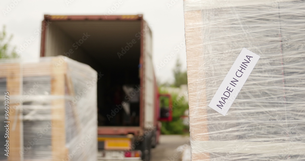 Forklift operator loading cargo to a container made in china sign in the foreground Forklift operator loading cargo to a container made in china sign in the foreground