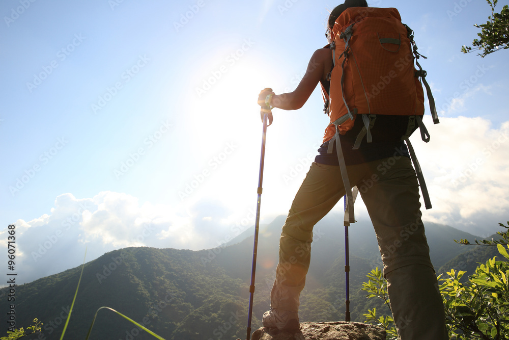 young woman backpacker hiking on mountain peak
