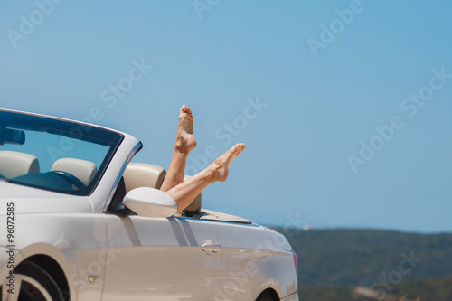Slender women's legs look out of car window.