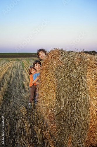 3 boys in a haystack in the field