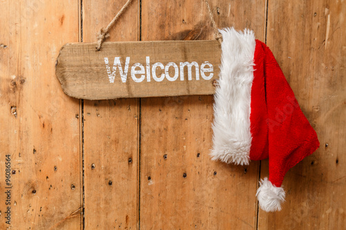 Red Santa hat hanging on a welcome  sign on an old front door