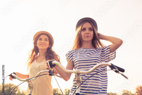 cherful happy girls with hat ride bicycles on the park