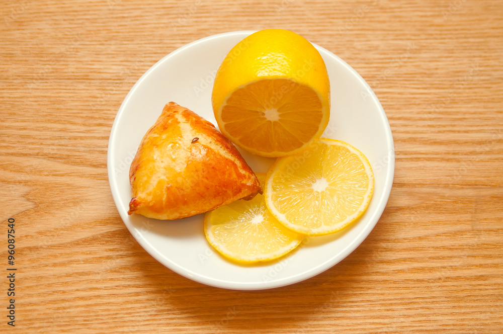 Lemon and bun on wooden background, top view Lemon and bun on wooden background, top view