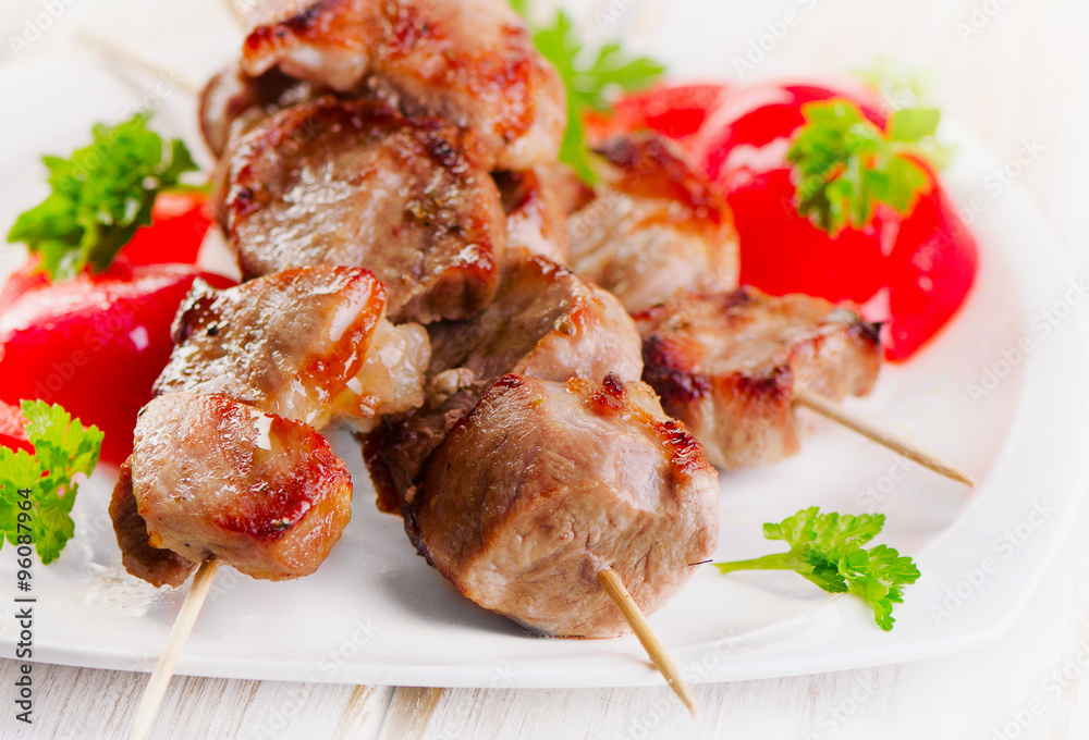 Kebabs served with vegetables on white plate Kebabs served with vegetables on white plate