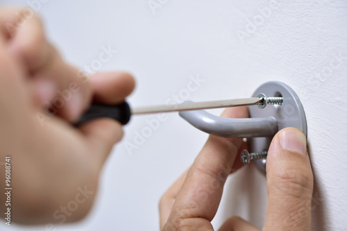 young man screwing a hook in the wall
