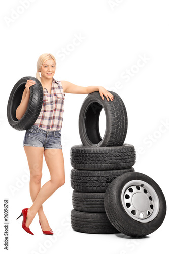 Female mechanic holding a car tire