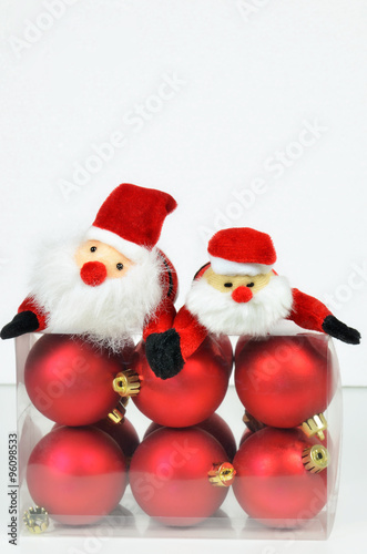Christmas Decoration / close up of a plastic box with red christmas tree balls and Santa Claus on white background, vertical 