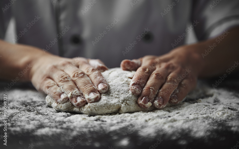 Close-up of woman baker hands kneading the dough on black board with flour powder. Concept of baking and patisserie.    - obrazy, fototapety, plakaty 