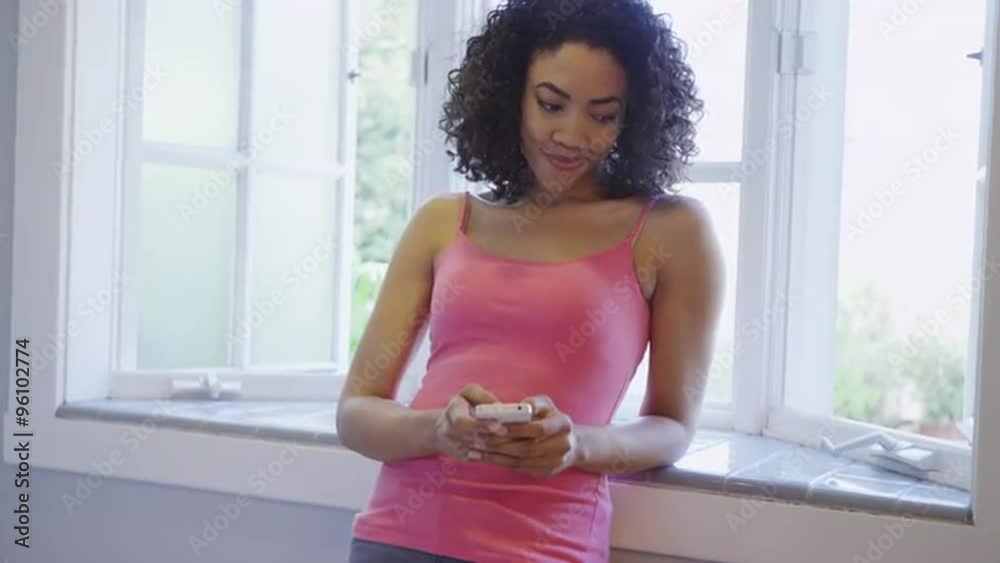 African woman texting on smartphone at home