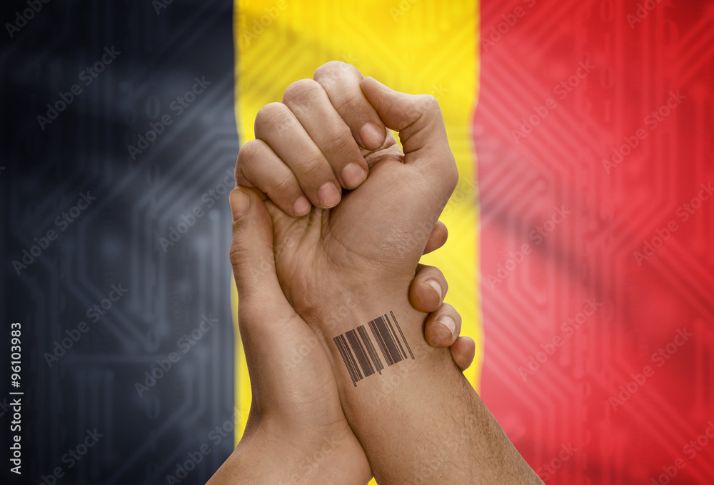 Barcode ID number on wrist of dark skinned person and national flag on background - Belgium