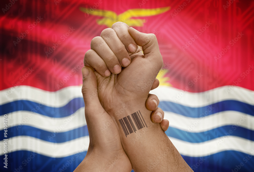 Barcode ID number on wrist of dark skinned person and national flag on background - Kiribati