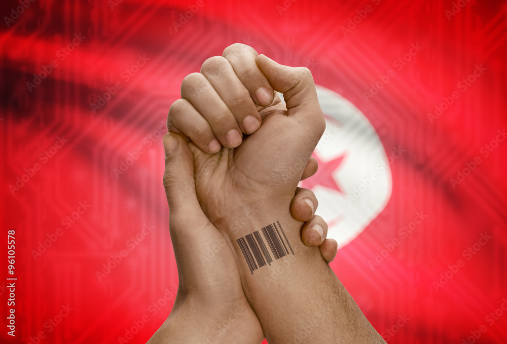 Barcode ID number on wrist of dark skinned person and national flag on background - Tunisia