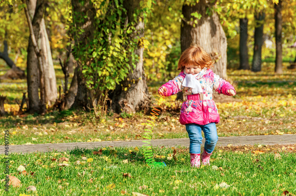 Girl playing in the park with a Rainbow spiral spring Girl playing in the park with a Rainbow spiral spring
