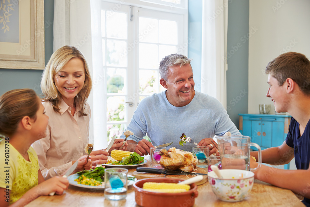 Family Sitting At Table Enjoying Meal At Home Together Family Sitting At Table Enjoying Meal At Home Together