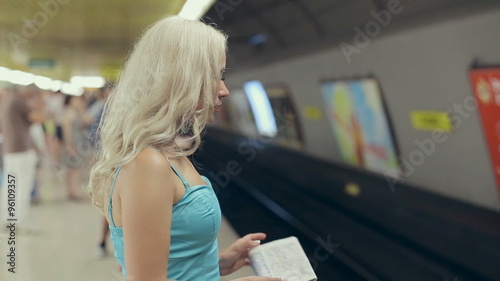 Cute blonde with a map in her hands waiting for the subway car