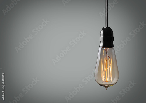 Vintage hanging light bulb over gray background photo