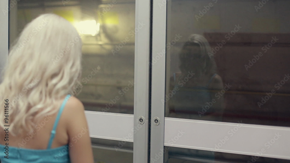 Beautiful young woman in front of the closed doors of the subway Beautiful young woman in front of the closed doors of the subway