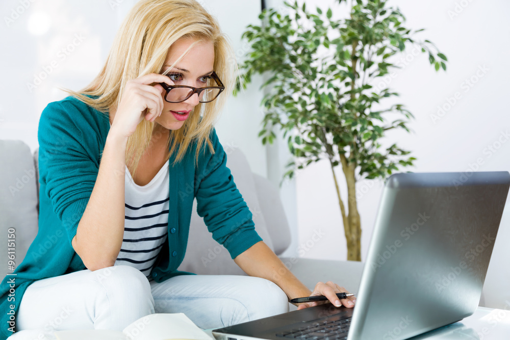 Pretty young woman working with laptop at home. Pretty young woman working with laptop at home.