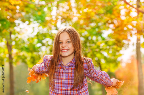 Happy little girl throw maple leaves in the air