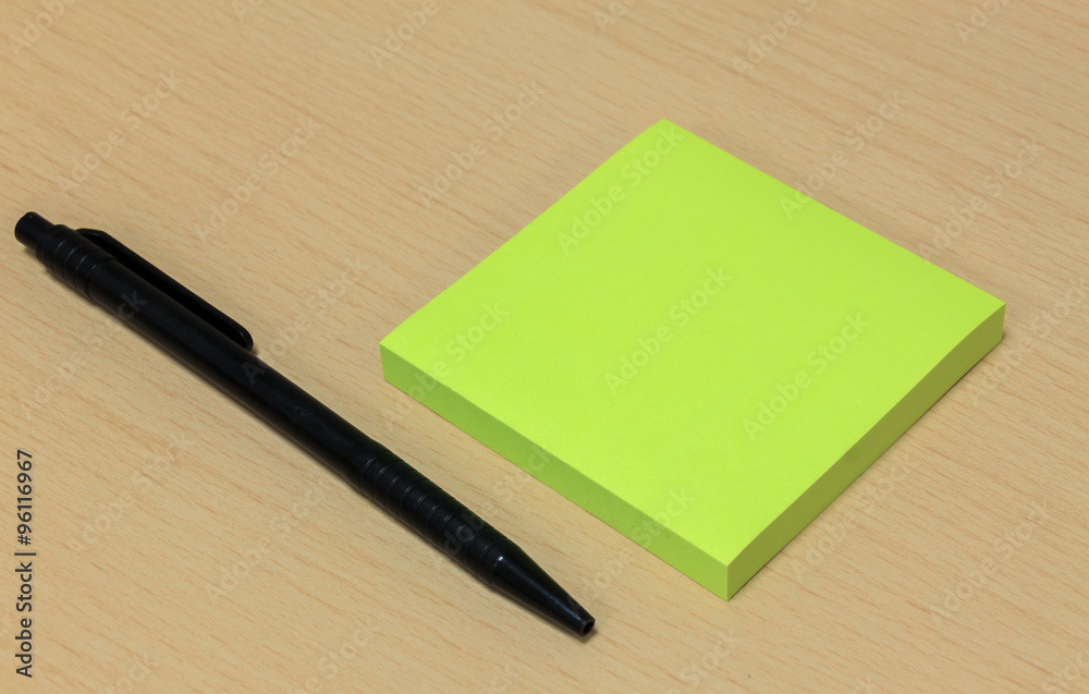 black pen,green paper on wood table background.