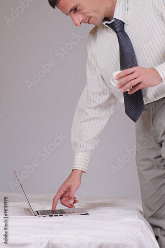 Businessman standing and working a home with laptop on bed. Businessman drinking morning coffee getting ready of work and checking his mail