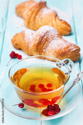 Tea with berries of a guelder-rose and fresh croissants