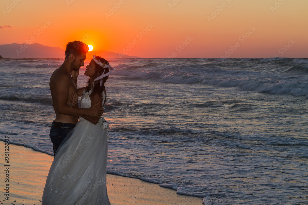 Fototapeta premium Just married young couple on a hazy beach at dusk.