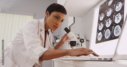 Young intelligent  female radiologist looking in a microscope photo
