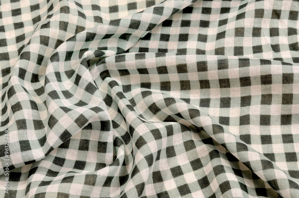 Close up on crumpled checkered tablecloth fabric. Green and white tartan square pattern as background. Close up on crumpled checkered tablecloth fabric. Green and white tartan square pattern as background.