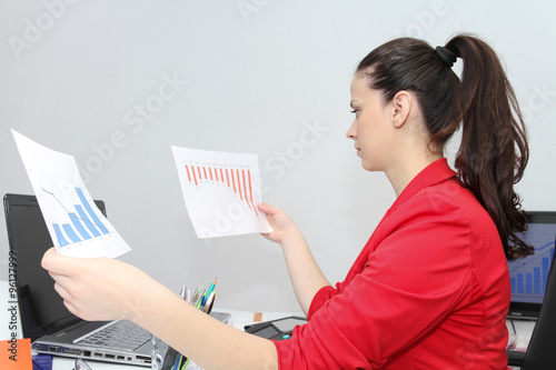 Pretty Business woman analyzing investment charts with calculato photo