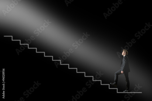 Businessman walking upwards towards the light on conceptual stai