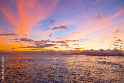 Sunset on a surfing beach in Honolulu  Hawaii. Tropical beach at sunset with surfers and boats.