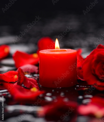 Beautiful red rose petals with candle and therapy stones 