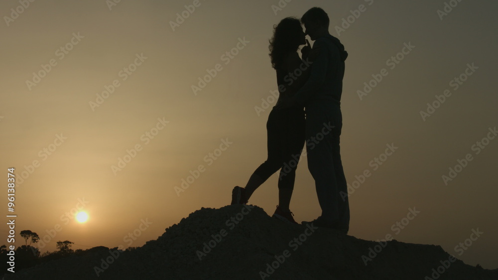 Romantic story of two people in love. Silhouette of couple kissing at sunset Romantic story of two people in love. Silhouette of couple kissing at sunset