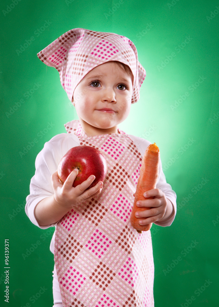 the baby girl with a kerchief and kitchen apron holding an vegetable isolated on the green background the baby girl with a kerchief and kitchen apron holding an vegetable isolated on the green background