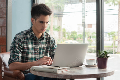 Businessman using laptop with tablet and pen on wooden table in photo