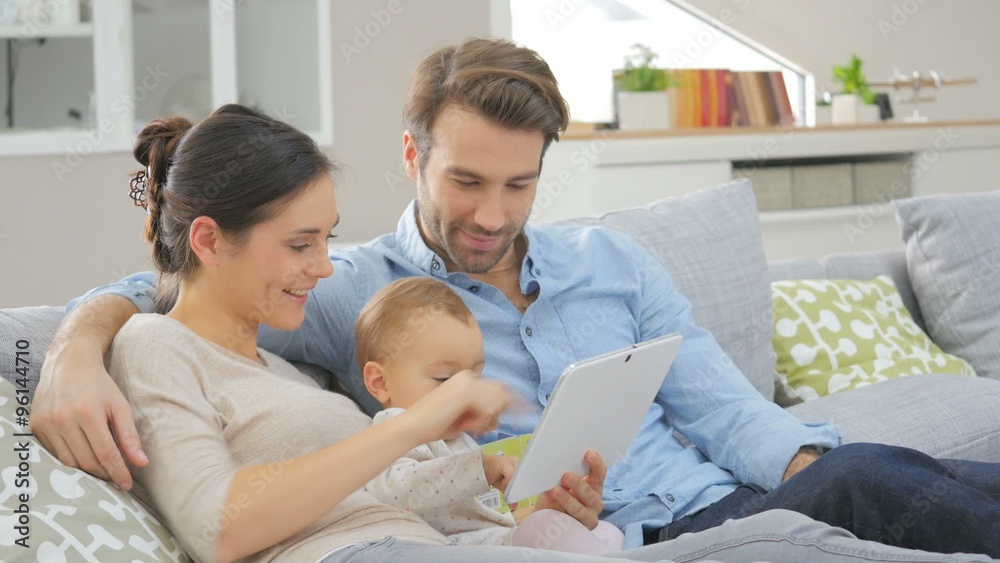 Parents with baby girl in sofa using digital tablet Parents with baby girl in sofa using digital tablet