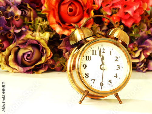 alarm clock with rose vintage flower background soft focus