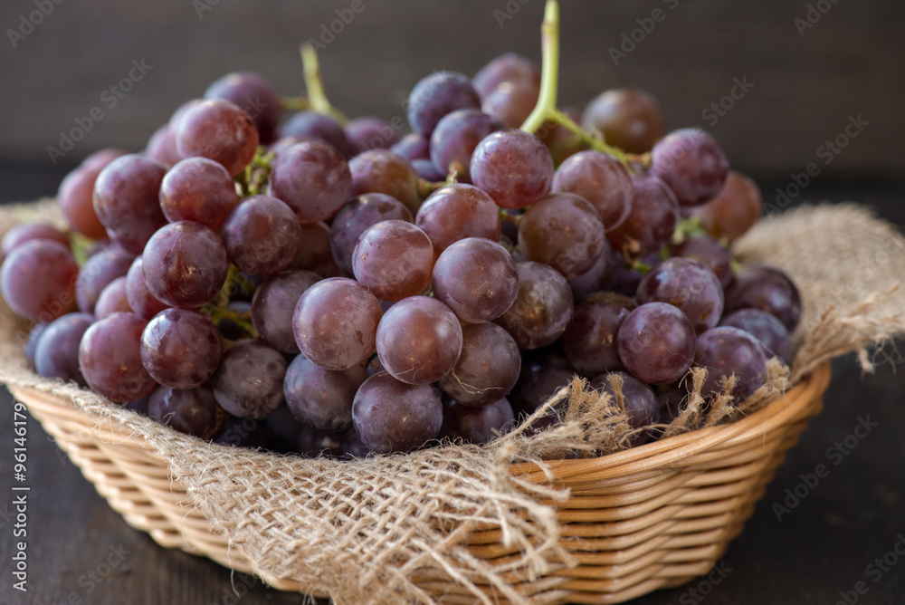 Bunch of grapes in the basket on wooden table Bunch of grapes in the basket on wooden table
