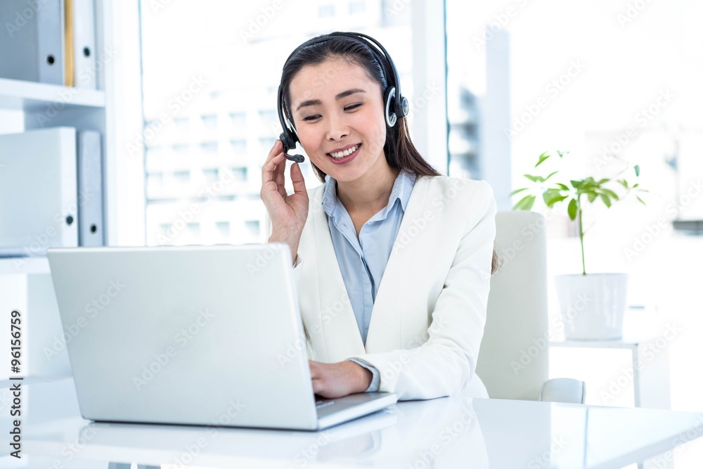 Smiling businesswoman with headset using laptop Smiling businesswoman with headset using laptop